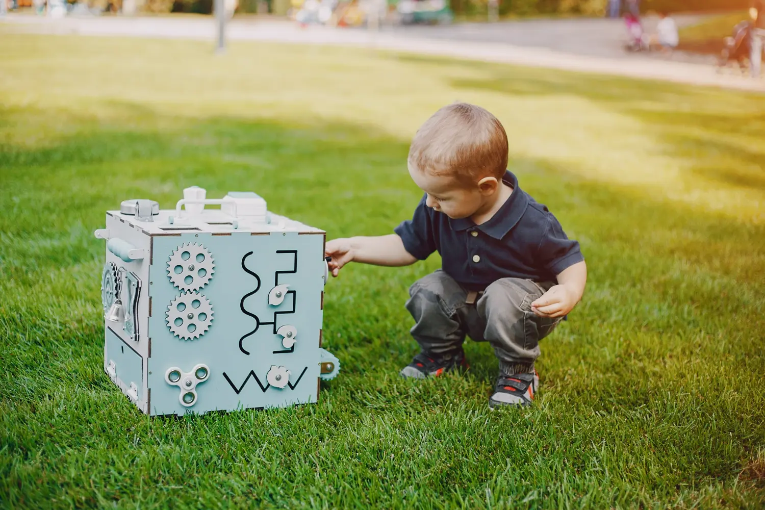 Young child playing with a sensory activity board outdoors to explore different textures and movements